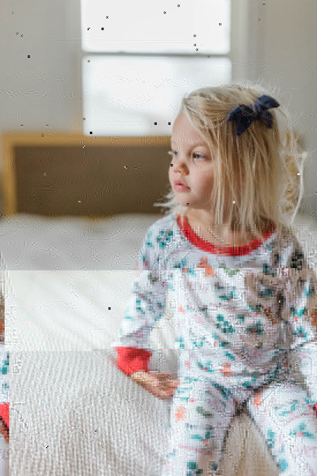 little girl wearing personalized Christmas PJ's with images of hot cocoa, gingerbread men, and holly leaves on a white background and red cuffs.