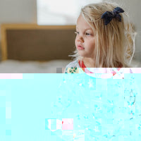 little girl wearing personalized Christmas PJ's with images of hot cocoa, gingerbread men, and holly leaves on a white background and red cuffs.