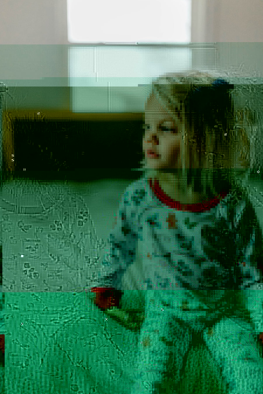 little girl wearing personalized Christmas PJ's with images of hot cocoa, gingerbread men, and holly leaves on a white background and red cuffs.